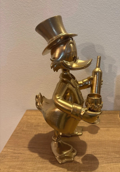 Dagobert Duck Statue mit Glas Wein und Flasche