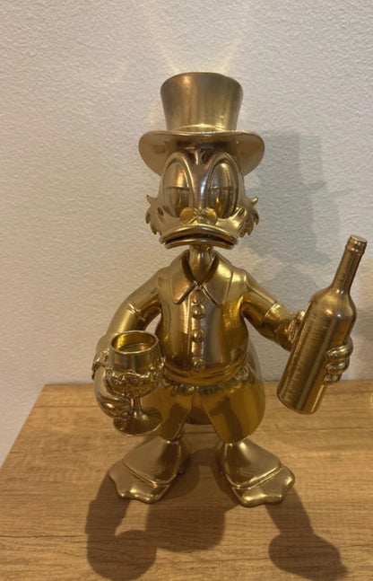 Dagobert Duck Statue mit Glas Wein und Flasche