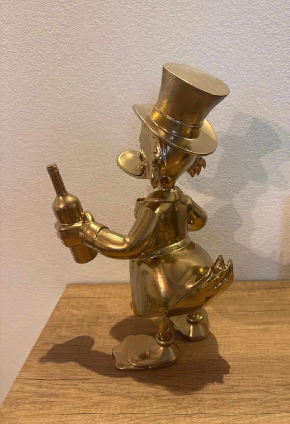 Dagobert Duck Statue mit Glas Wein und Flasche