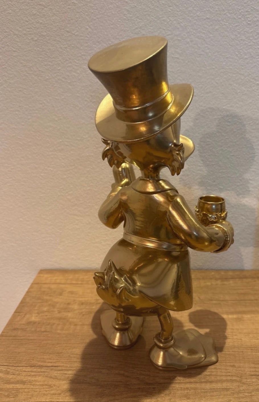 Dagobert Duck Statue mit Glas Wein und Flasche